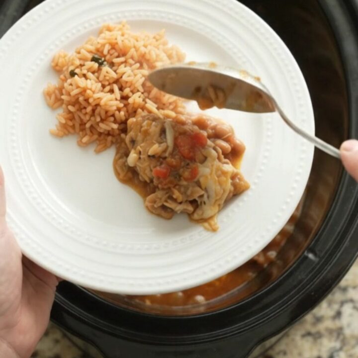 Slow cooker filled with shredded chicken, beans, and melted Oaxaca cheese, topped with blistered cheese.