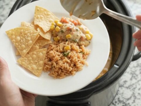 Slow cooker chicken thighs in a creamy pepper jack queso with green chiles and corn, served in the crockpot.