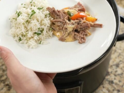 Shredded beef barbacoa with melted cheddar and peppers in a slow cooker