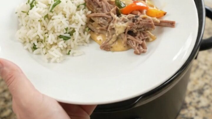 Shredded beef barbacoa with melted cheddar and peppers in a slow cooker