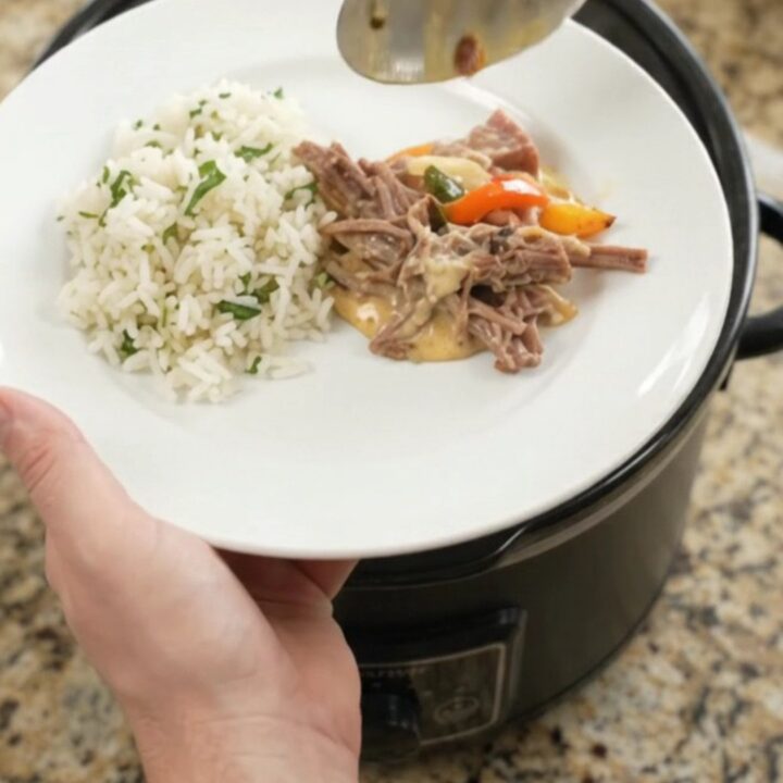Shredded beef barbacoa with melted cheddar and peppers in a slow cooker