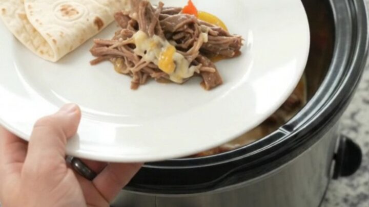 Slow cooker fajita beef barbacoa with melted Monterey Jack and peppers in a black Crockpot