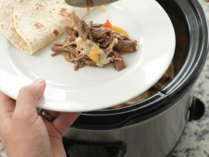 Slow cooker fajita beef barbacoa with melted Monterey Jack and peppers in a black Crockpot