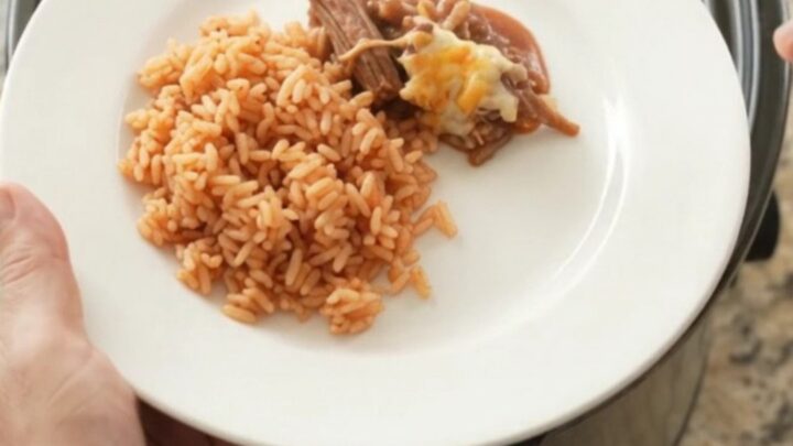 Slow cooker beef barbacoa with melted Oaxaca cheese and red sauce in a black crockpot