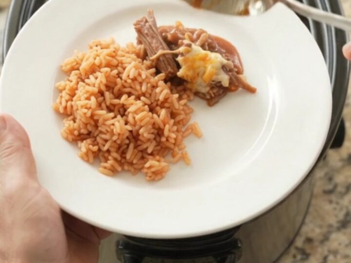 Slow cooker beef barbacoa with melted Oaxaca cheese and red sauce in a black crockpot