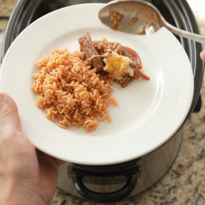 Slow cooker beef barbacoa with melted Oaxaca cheese and red sauce in a black crockpot