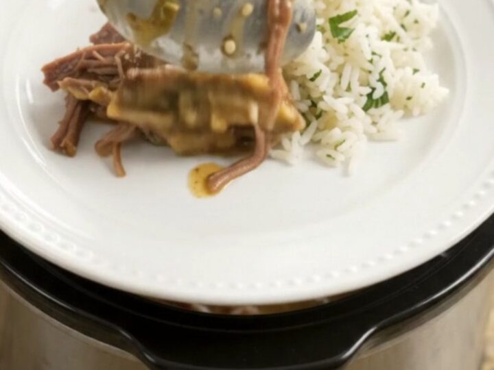 Shredded beef barbacoa in a slow cooker with creamy green sauce and melted cheddar