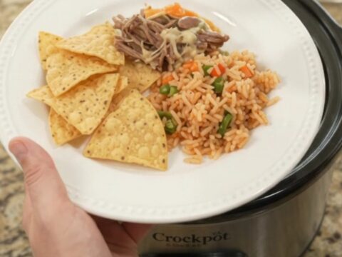 Slow cooker full of shredded beef barbacoa with peppers and melted cheese sauce