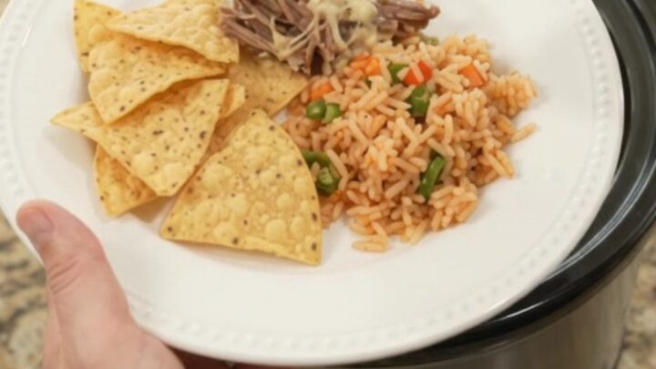 Slow cooker full of shredded beef barbacoa with peppers and melted cheese sauce
