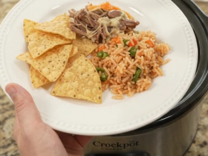 Slow cooker full of shredded beef barbacoa with peppers and melted cheese sauce