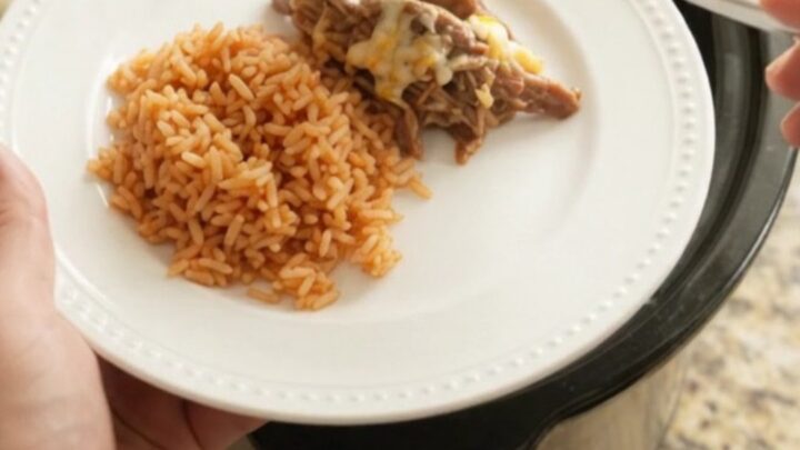 Slow cooker filled with shredded beef barbacoa topped with melted cheese and pineapple