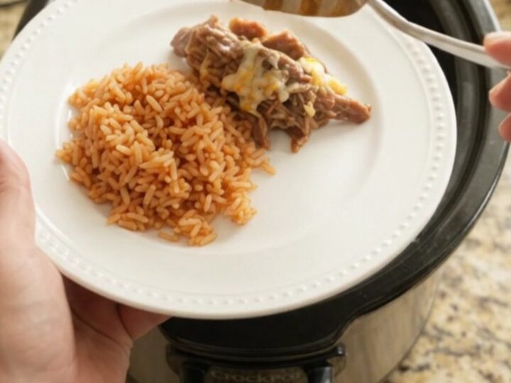 Slow cooker filled with shredded beef barbacoa topped with melted cheese and pineapple