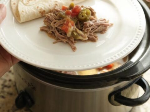 Slow cooker beef barbacoa with creamy tomato-jalapeño sauce in a black crockpot