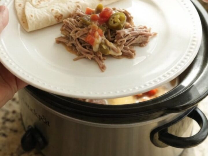 Slow cooker beef barbacoa with creamy tomato-jalapeño sauce in a black crockpot