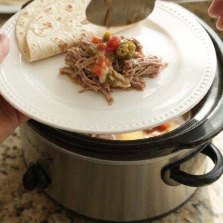Slow cooker beef barbacoa with creamy tomato-jalapeño sauce in a black crockpot