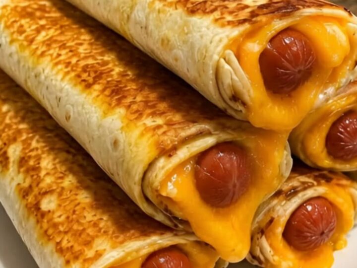 A stack of crispy golden-brown hot dog cheddar wraps on a white plate with melted cheese oozing out.