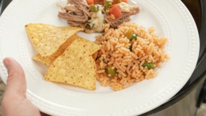 Slow cooker beef barbacoa with melted cheese and jalapeños in a black crockpot