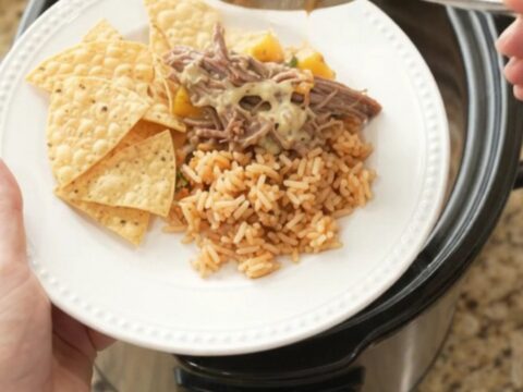 Shredded beef barbacoa in a slow cooker with creamy queso sauce