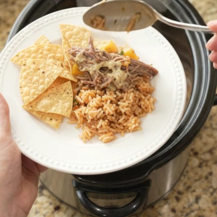 Shredded beef barbacoa in a slow cooker with creamy queso sauce