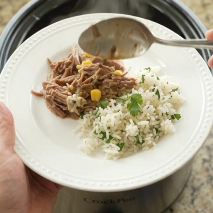 Shredded beef barbacoa in creamy cheese sauce with green chiles and corn in a slow cooker
