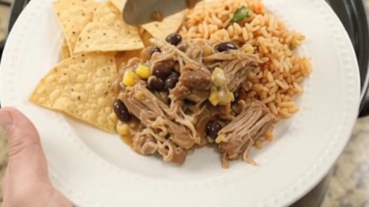 Slow cooker pork carnitas with black beans and cheese sauce in a black crockpot