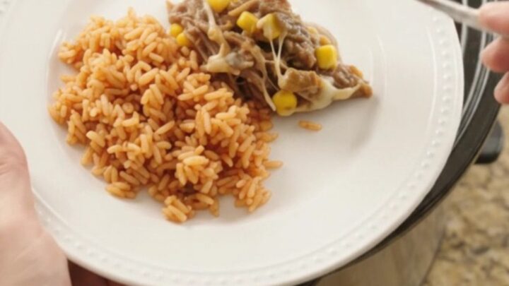 Crockpot full of shredded beef barbacoa with melted Oaxaca cheese, green chiles, and corn