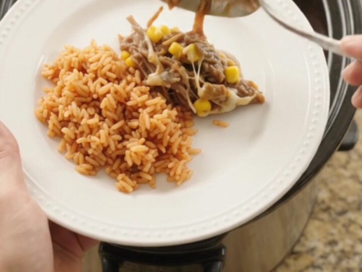 Crockpot full of shredded beef barbacoa with melted Oaxaca cheese, green chiles, and corn