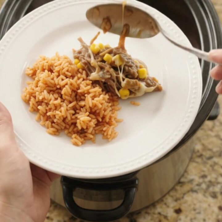 Crockpot full of shredded beef barbacoa with melted Oaxaca cheese, green chiles, and corn