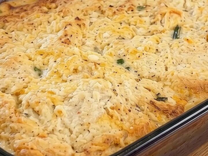 A golden brown cheddar biscuit chicken pot pie bake in a glass dish with steam rising from the crust