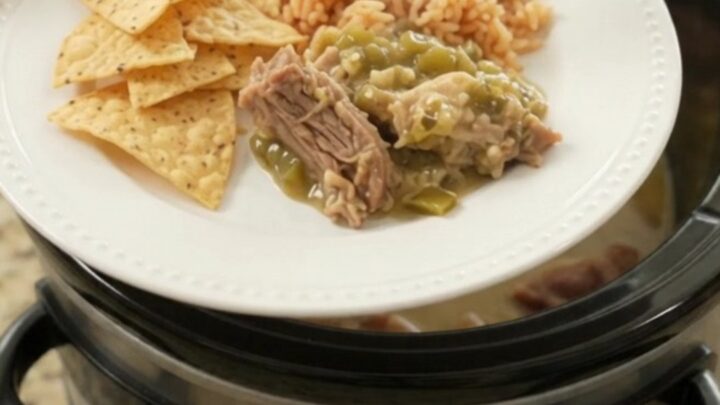 Slow cooker full of creamy salsa verde pork carnitas with melted cheese and steam rising
