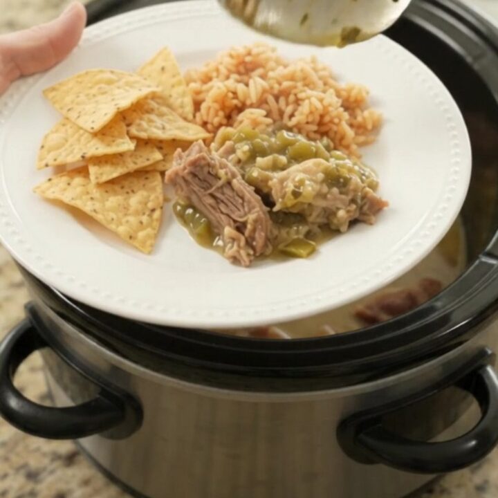 Slow cooker full of creamy salsa verde pork carnitas with melted cheese and steam rising