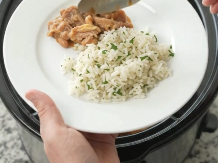 Slow cooker pork carnitas in a creamy red enchilada sauce with pinto beans, topped with melted cheddar and cream cheese