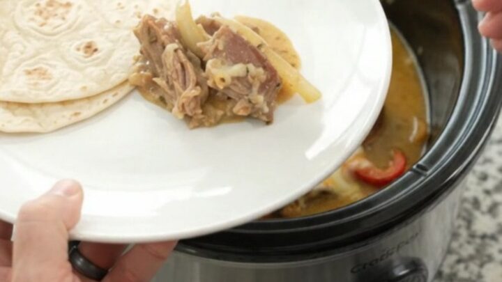 Slow-cooker fajita pork carnitas with creamy Monterey Jack sauce in a black crockpot