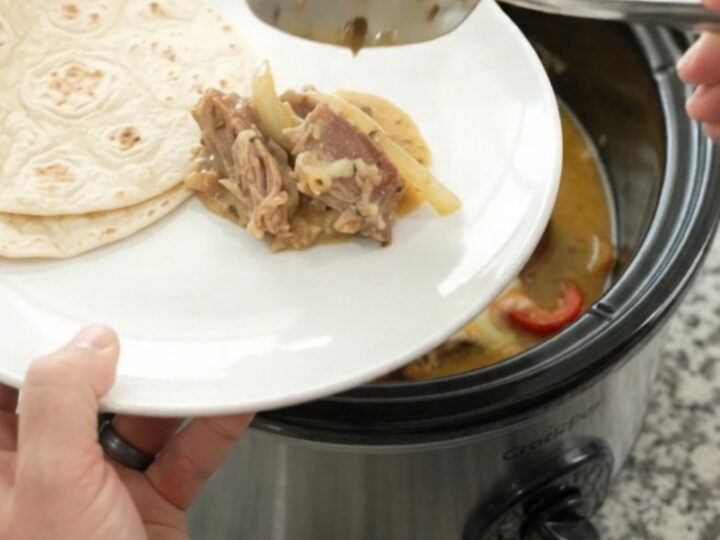 Slow-cooker fajita pork carnitas with creamy Monterey Jack sauce in a black crockpot