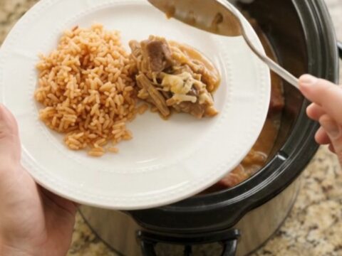 Slow cooker filled with shredded pork carnitas topped with melted cheese and pineapple