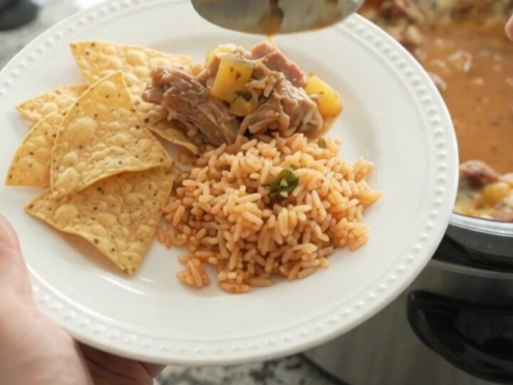 A slow cooker filled with creamy chipotle pineapple pork carnitas, topped with melted cheese and steam rising.