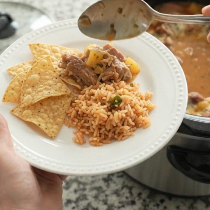 A slow cooker filled with creamy chipotle pineapple pork carnitas, topped with melted cheese and steam rising.