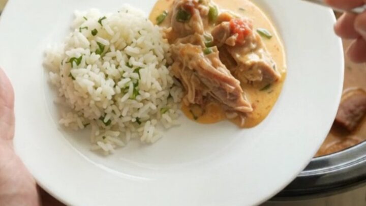 Slow cooker filled with creamy pork carnitas, topped with melted cheddar and jalapeños.