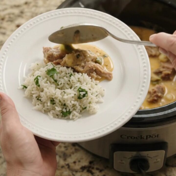 Slow cooker full of creamy cheddar poblano pork carnitas with hominy, steam rising