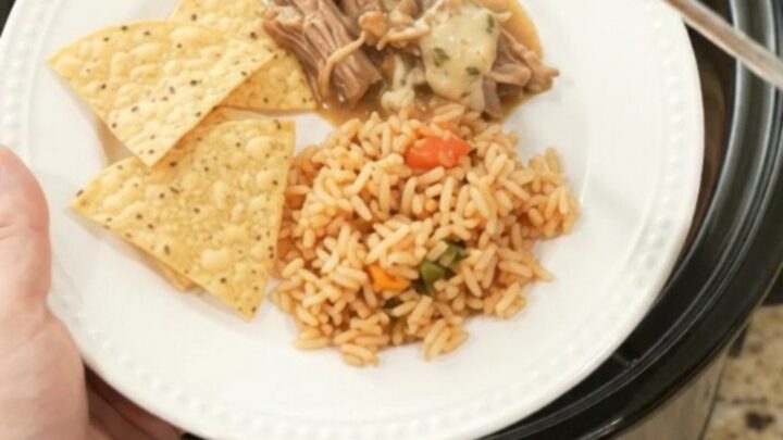 Slow cooker filled with shredded pork in a creamy pepper jack sauce, topped with melted cheese and beans.