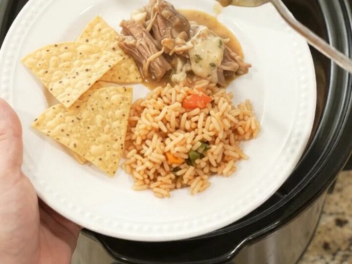 Slow cooker filled with shredded pork in a creamy pepper jack sauce, topped with melted cheese and beans.