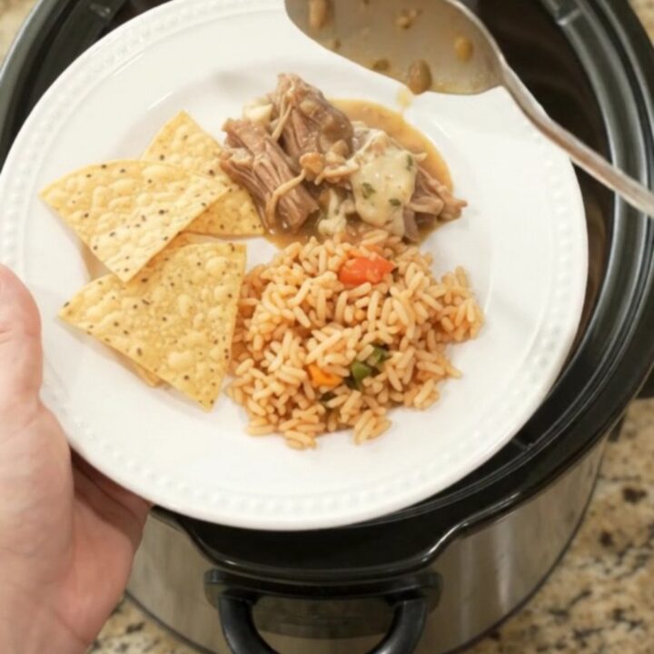 Slow cooker filled with shredded pork in a creamy pepper jack sauce, topped with melted cheese and beans.