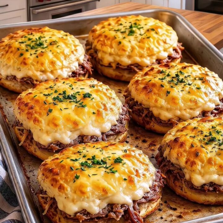 Close-up of a cheesy roast beef biscuit melt being pulled apart with visible steam and melted cheese.