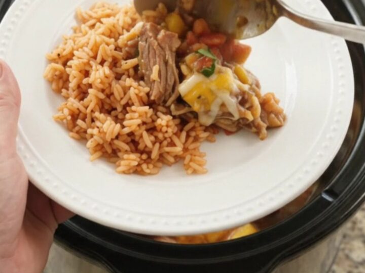 Slow cooker filled with bubbling mango habanero pork carnitas topped with melted cheese