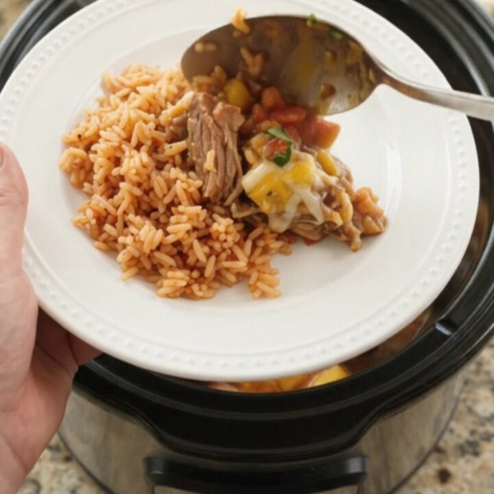 Slow cooker filled with bubbling mango habanero pork carnitas topped with melted cheese