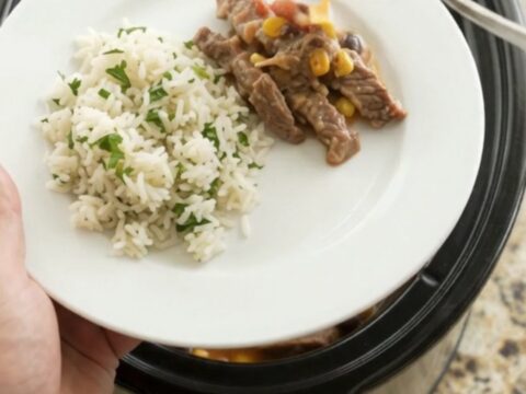 A slow cooker filled with tender skirt steak, black beans, and corn in a creamy cheddar sauce.