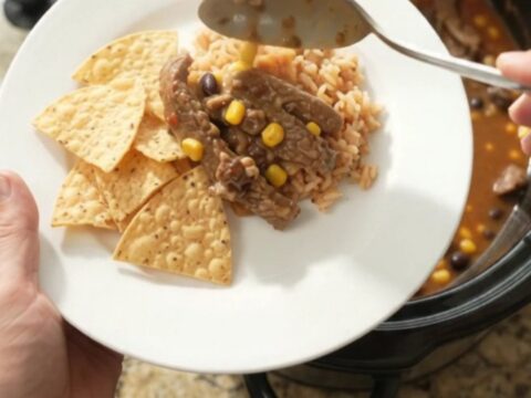 Slow cooker filled with tender skirt steak, black beans, corn, and melted pepper jack queso sauce