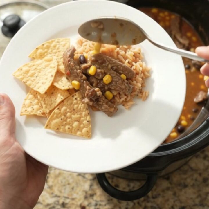 Slow cooker filled with tender skirt steak, black beans, corn, and melted pepper jack queso sauce