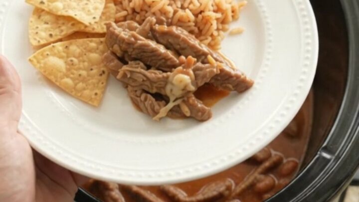 Bubbling Crockpot of pepper jack red enchilada skirt steak with melted cheese and sauce