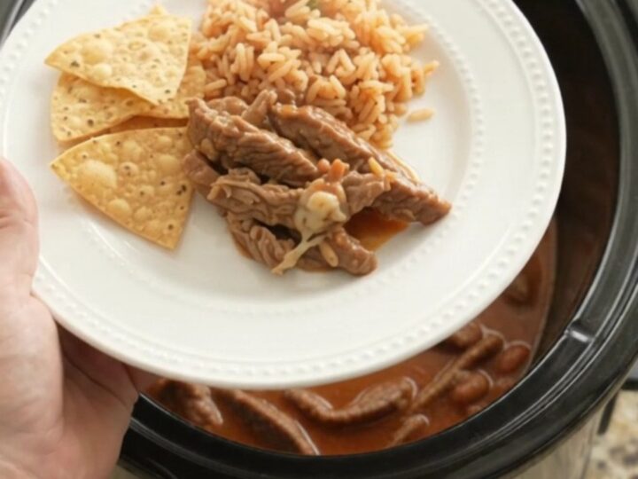 Bubbling Crockpot of pepper jack red enchilada skirt steak with melted cheese and sauce